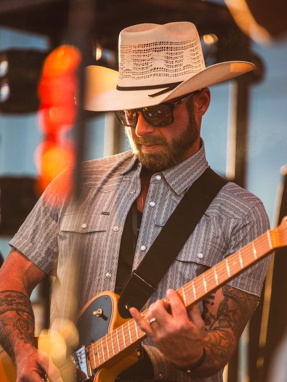 Elliott Sublett, owner of Sunny Shades, playing guitar on stage at sunset