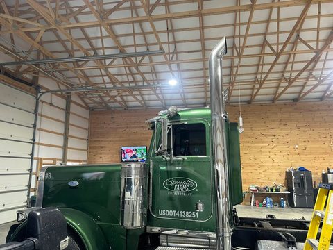 Dark green custom semi tractor with tinted glass inside a shop