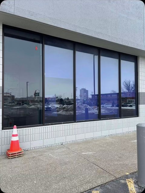 Long band of tinted storefront windows on a white brick building