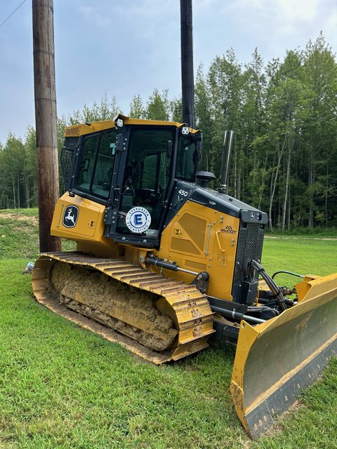 Yellow crawler dozer with tinted cab glass parked on grass
