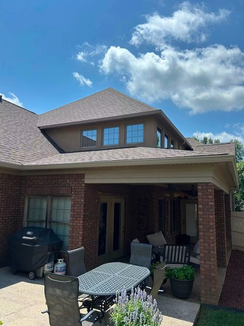 Brick home with tinted upper windows above a covered patio